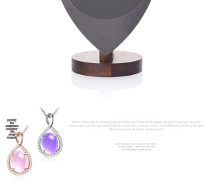 Detailed close-up of water drop gemstone pendants on a walnut wood jewelry display stand