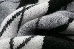 Macro detail of diamond pattern knit fabric texture in black grey and white colors