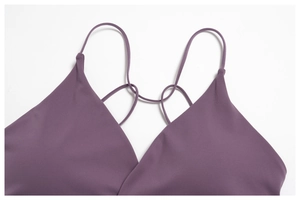 Macro detail of plum purple yoga vest featuring crisscross straps and thin shoulder design