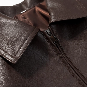 Close-up of the lapel and metal zipper on a dark brown faux leather jacket texture