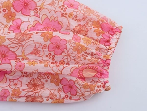 Dettaglio dei polsini elastici a balze su un abito in chiffon a fiori rosa delicato