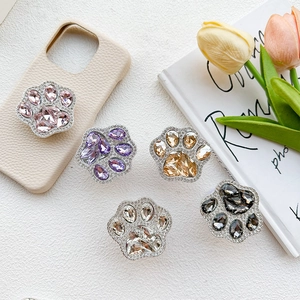 Macro detail of luxury rhinestone cat paw phone grips in various colors on textured background