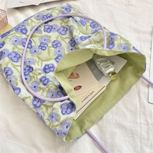 Dettaglio della borsa a fiori viola con fodera verde e manici in corda color lavanda