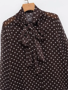 Detail of sheer chiffon fabric with polka dot pattern and tie-neck bow on blouse