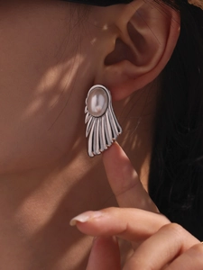Detail view of a silver fan-shaped earring with white pearl on ear lobe
