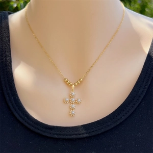 Golden 18K gold plated cross necklace with white pearls worn by a model on black shirt