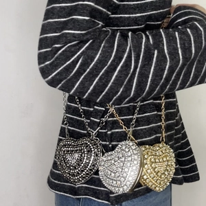 Close-up of heart-shaped rhinestone mini bags in black, silver, and gold with chain straps