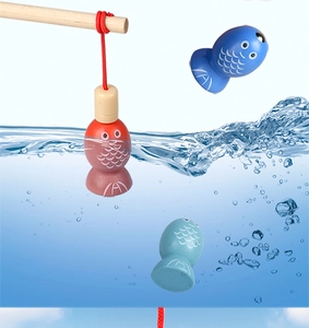 Close-up of magnetic wooden fishing rod catching colorful toy fish over blue water