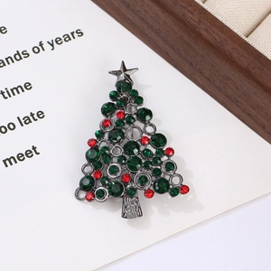 Close-up of a Christmas tree brooch with green and red rhinestones on a festive card