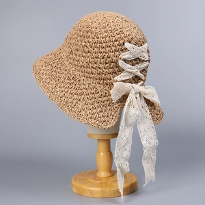 Detail of woven straw sun hat featuring elegant white lace ribbons and a stylish bow knot