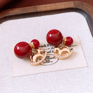 Macro detail of 18K gold plated rocking horse earrings with red beads and small crystals