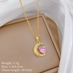 Detailed view of gold necklace with pink heart gem and crystal-encrusted moon pendant