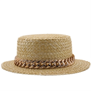 Détail d'un chapeau de paille à bord plat avec décoration de grosse chaîne or rose