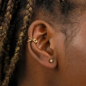 Vue macro de la manchette d'oreille dorée et du clou d'oreille avec gemme vert clair