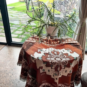 Detail of woven bohemian geometric blanket with tassels on a wooden table setup