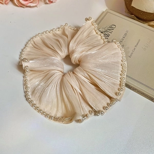 Close-up of champagne silk hair scrunchie with pearl edges on a vintage book