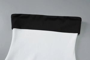 Close-up of contrast stitching on a black and white strapless bodycon dress bodice