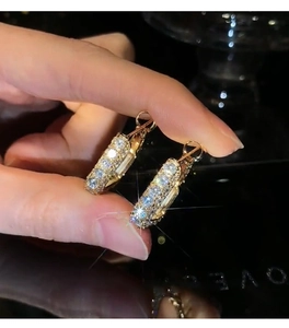 Close-up of golden hoop earrings with pavé cubic zirconia held against dark background