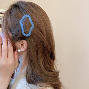 Close-up of a blue denim wavy hair clip worn by a woman with pearl earrings and necklace