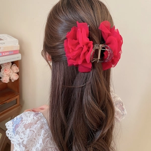 Detail der roten Stoffblumen-Haarklammer in langem gewelltem Haar im eleganten Stil