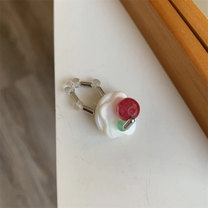 Macro shot of handcrafted beaded ring with red and green beads on a white resin base