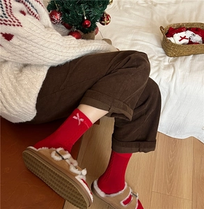 Close-up of red festive cotton socks with white bow embroidery in a cozy winter setting