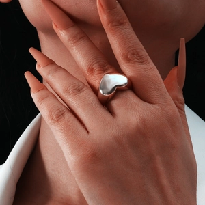 Macro shot of a high-polished silver heart ring showcasing smooth metallic textures