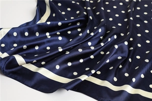 Detail of navy blue silk scarf fabric featuring white polka dots and a border