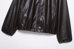 Detail view of brown faux leather jacket featuring smooth zipper and side pockets