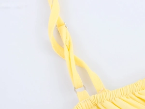 Détail de robe jaune montrant des bretelles fines avec des anneaux en métal argenté