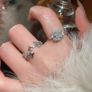 Detailed close-up of silver flower and star rings with blue zircon on model's hand