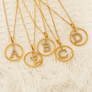 Gold plated initial necklaces A-E with cubic zirconia inlays on white plush background