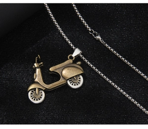 Close-up of vintage bronze motorcycle pendant with fine details on a black textured background