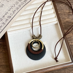 Detail of vintage wooden beads and bronze rings pendant on a dark leather cord