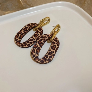 Close-up of leopard print resin earrings with golden metal chains on white tray