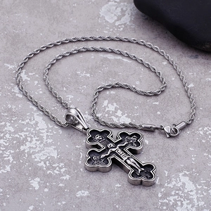 Detail shot of vintage silver cross pendant with embossed pattern on twisted chain