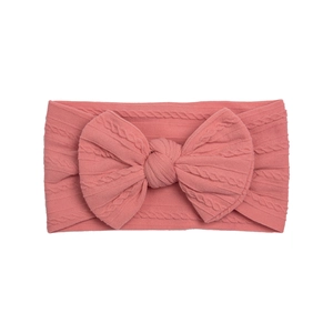 Close-up of coral pink nylon baby headband showing cable knit texture and large bow