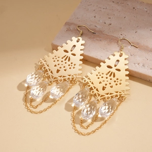Détail des boucles d'oreilles dorées à pampilles avec motifs géométriques et cristaux