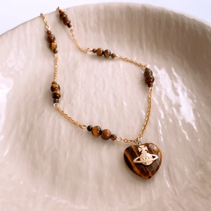 Detailed view of heart-shaped tiger eye stone pendant with golden metallic planet logo