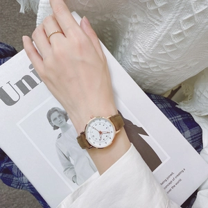 Close-up of minimalist gold quartz watch with brown suede strap and white dial