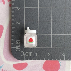 Detailed macro view of 1.5cm miniature resin juice bottle with glitter and watermelon decal