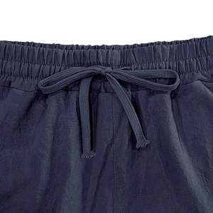 Detail of drawstring elastic waist on navy blue linen pants with visible textile texture