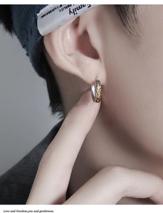 Detailed view of two-tone gold and silver flame hoop earring on male model's ear