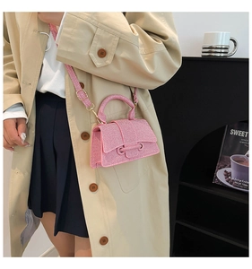 Détail du mini sac à main rose avec surface texturée et bandoulière porté par un modèle