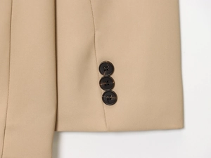 Detail of khaki blazer sleeve with three dark brown buttons on premium twill fabric