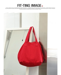 Detailed view of a red canvas tote bag hanging on a mirror frame in a minimalist room