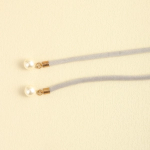 Close-up of grey velvet choker rope with gold metal end caps and creamy white pearl detail