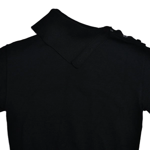 Detailed close-up of black knit sweater featuring a folded turtleneck and buttoned shoulder