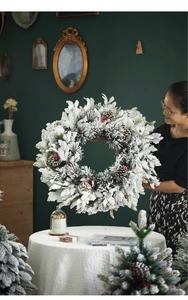 Detail of high-density flocked Christmas wreath with natural pine cones and red berries