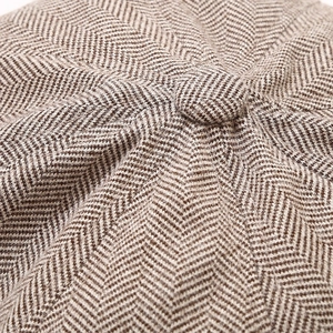 Classic brown herringbone newsboy cap featuring a detailed top button and wool texture